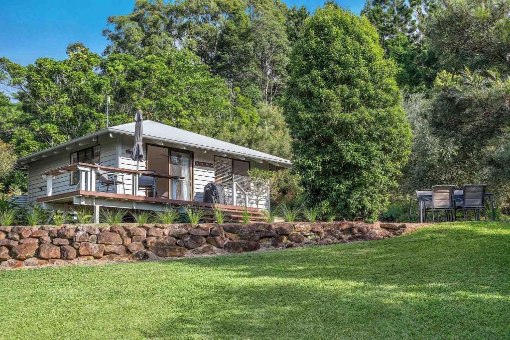 a small house with a stone wall in front of a yard at Twin Tallows - secluded couples retreat in Bangalow