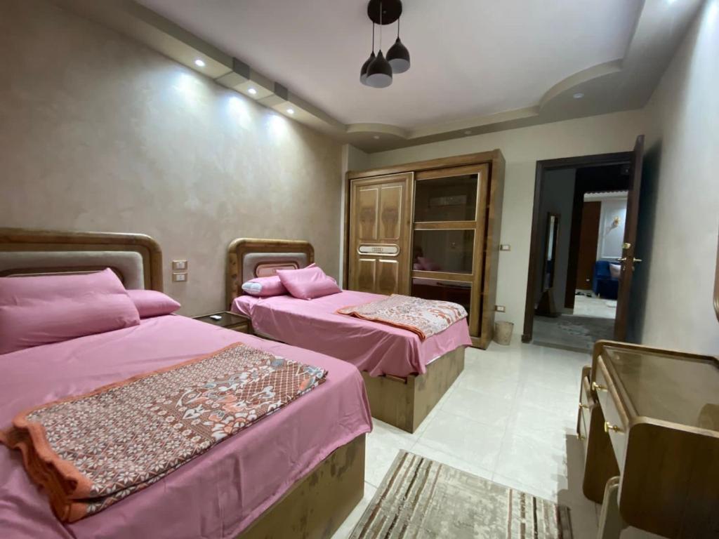 two beds in a room with pink sheets at شقه حديثة مكيفه بالكامل فرش مودرن حديث بكومبوند جاردينيا سيتي in Cairo