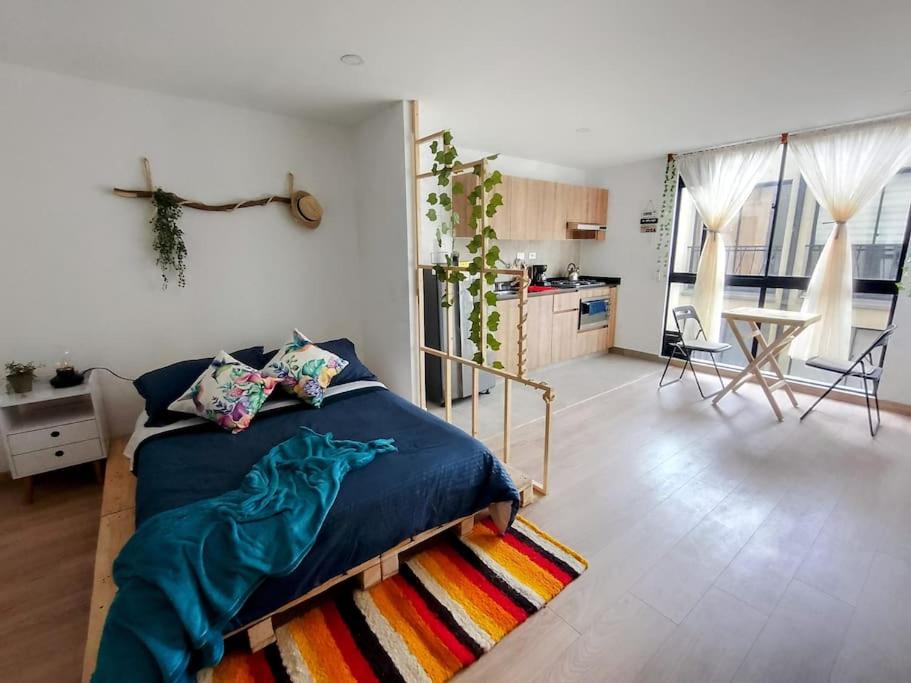 a bedroom with a blue bed and a kitchen at Loft Paraiso Vintage in Bogotá