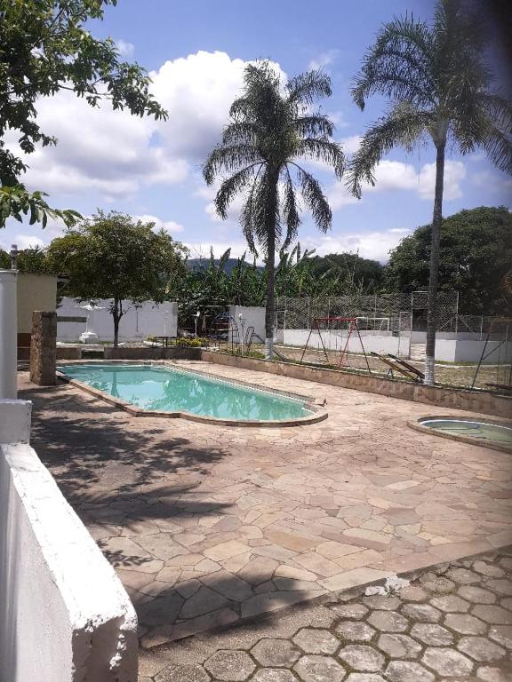 a swimming pool in a yard with palm trees at CHÁCARA PARA ROMEIROS- próximo ao santuário de nossa senhora in Roseira
