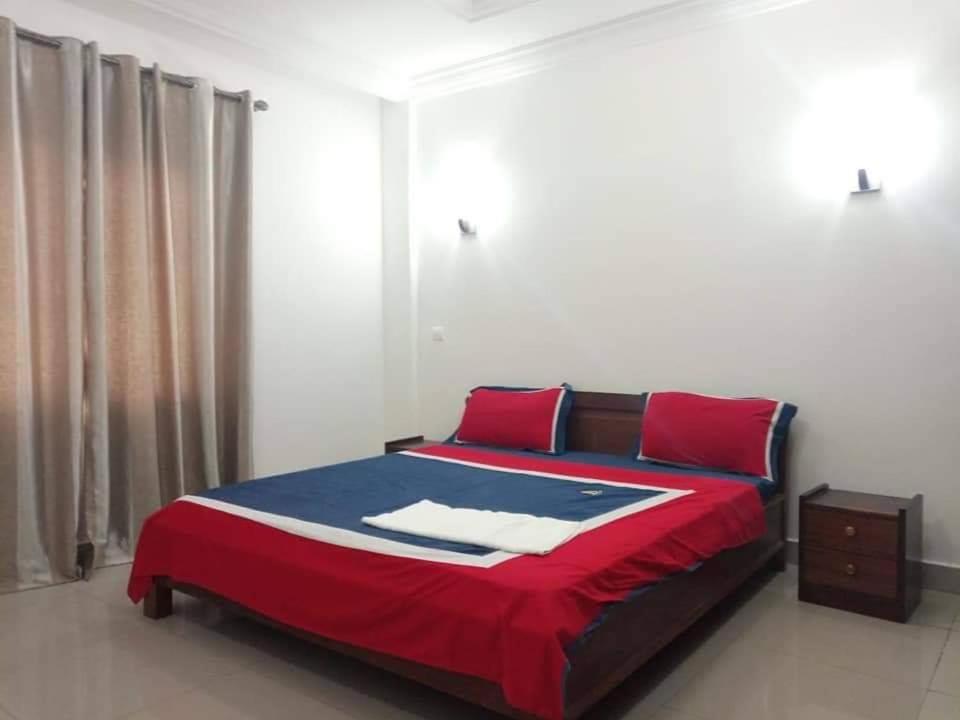- une chambre dotée d'un lit avec des draps rouges et bleus dans l'établissement Appartement bord de mer, à Pointe-Noire