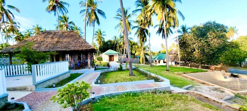 a resort with palm trees and a building at Mafia Neptune Villa Lodge in Utende