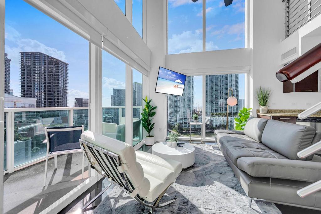 a living room with a couch and chairs and windows at Iconic 2 BR LOFT Brickell-Stunning views in Miami