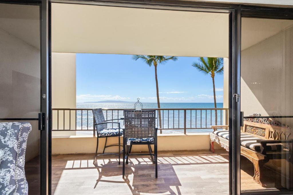 Un balcón con sillas y vista al mar. en Sugar Beach 333 - MCH, en Kihei