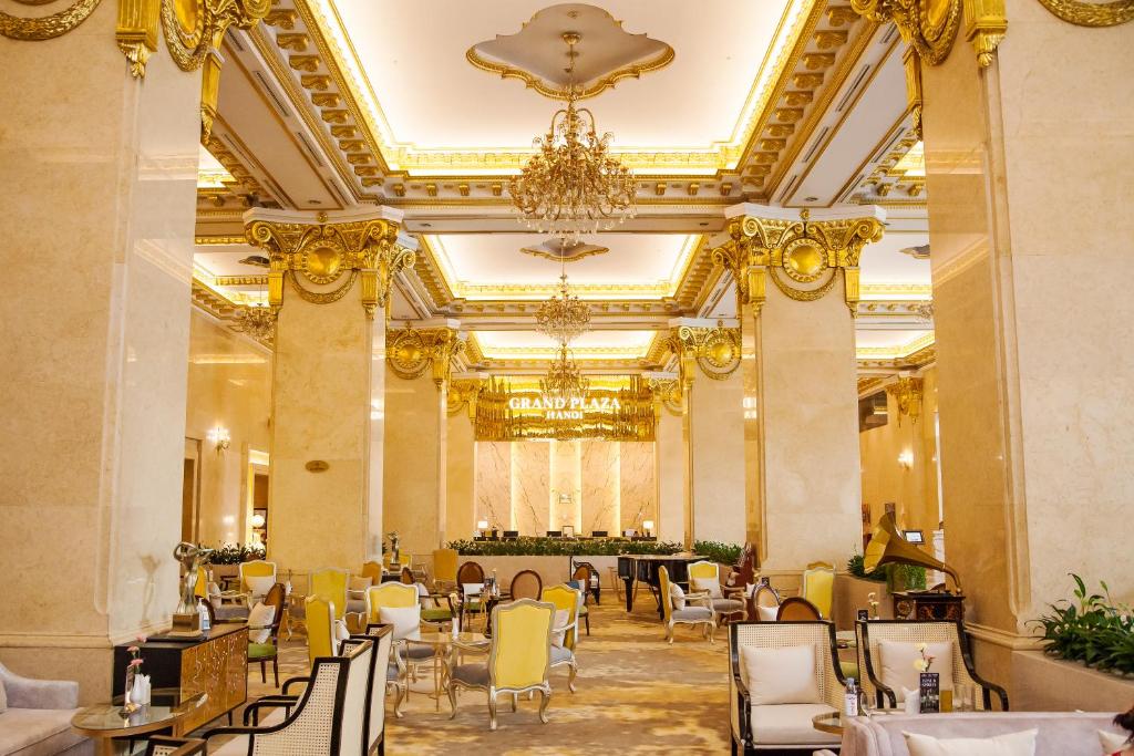 a dining room with yellow chairs and a chandelier at Grand Plaza Hanoi Hotel in Hanoi