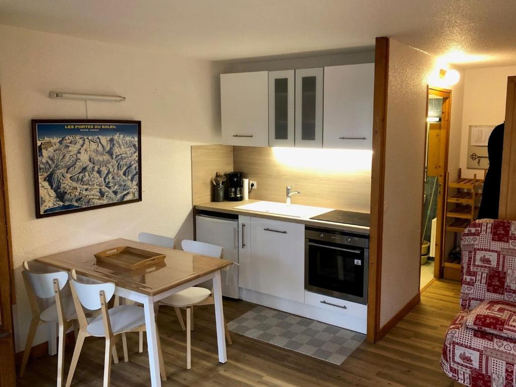une cuisine avec une table et des chaises et une cuisine avec un évier dans l'établissement Studio 4 pers, à 300m du centre, Parking - FR-1-676-47, à Châtel