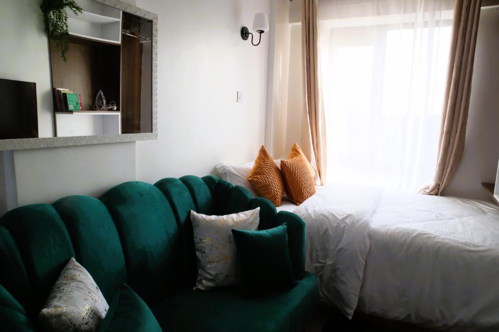 a living room with a green couch and a bed at El Hogar II in Kiambu