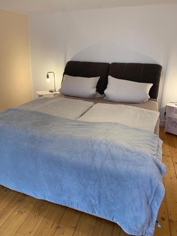 WolfhagenにあるFerienwohnung im Fachwerkhaus, 3 Schlafzimmer, Balkon, Garten, Parkplatz - Wohnung 2の大型ベッド1台(青い毛布、枕2つ付)