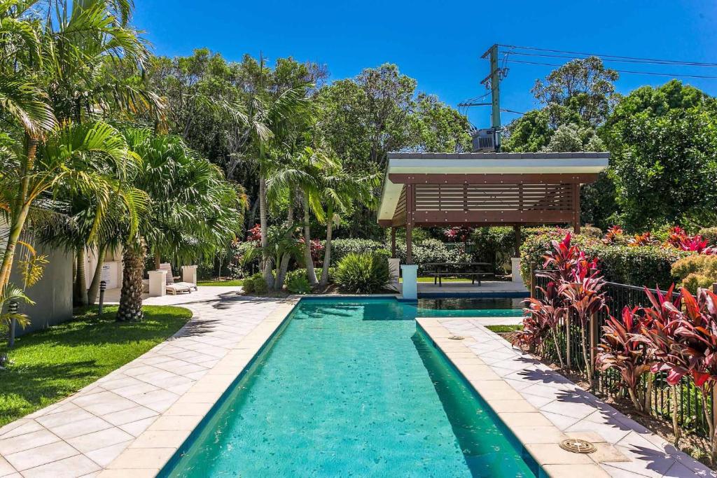 a swimming pool in a yard with trees and flowers at A Perfect Stay - Drift in Byron Bay