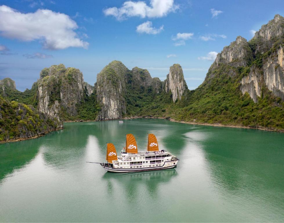 a boat on a river with mountains in the background at Paradise Peak Cruise in Ha Long