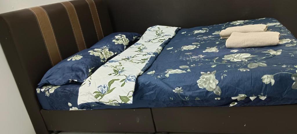 a bed with a blue comforter with flowers on it at Inap Mudah in Seri Iskandar