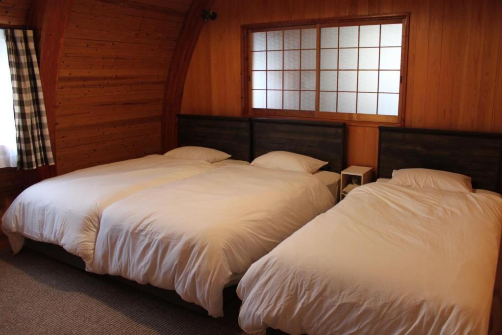 two beds in a room with two windows at Nagashima cottage - Vacation STAY 9014 in Kuwana