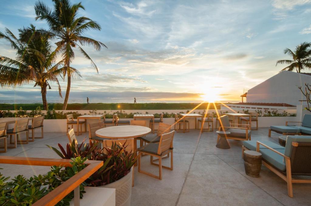 a patio with tables and chairs and the sunset at The Charleston in Galle