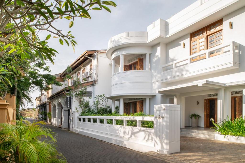 a white building with balconies on a street at The Charleston in Galle
