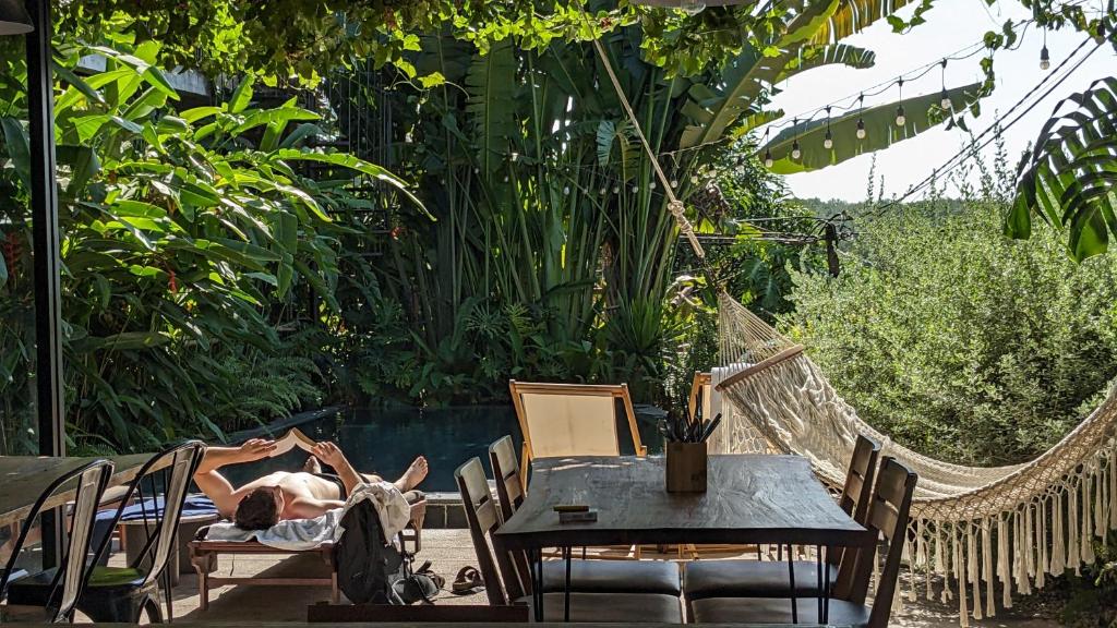 a man laying in a hammock in a garden at NANO ECO-HOSTEL in Hue