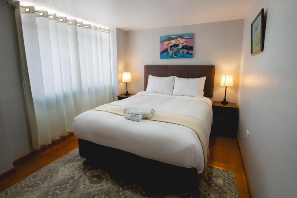 una camera da letto con un grande letto bianco con due lampade di Casa Hotel Lago Titicaca a Puno