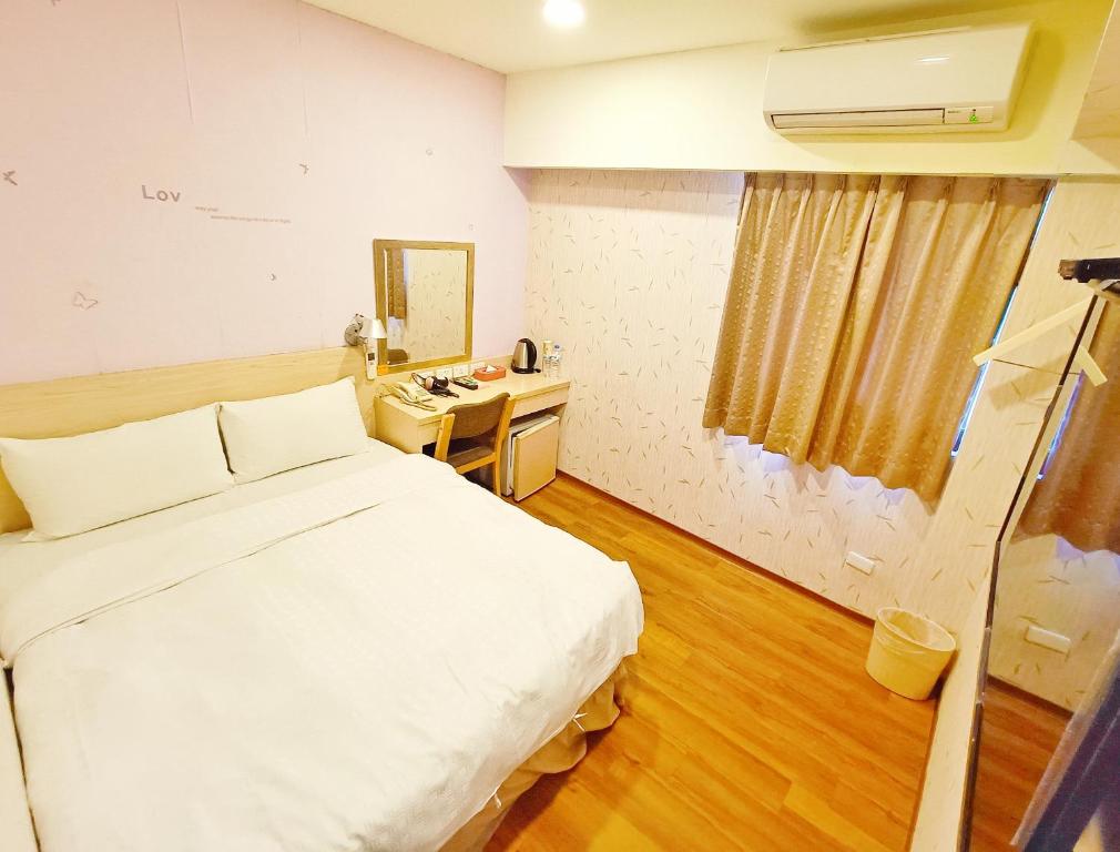a bedroom with a bed and a desk with a mirror at Sanduo Hotel in Kaohsiung