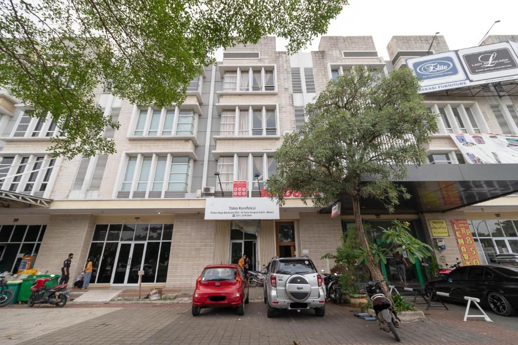 a building with two cars parked in front of it at RedDoorz near Universitas Esa Unggul Bekasi Harapan Indah in Bekasi