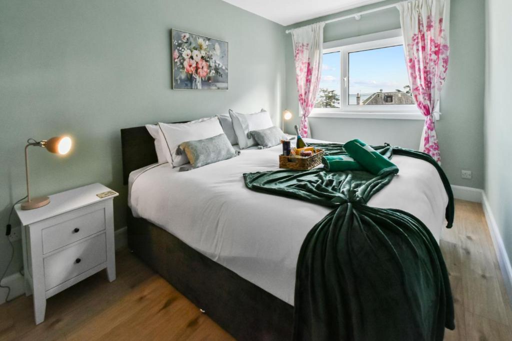 um quarto com uma cama grande com lençóis brancos e uma janela em Blacksand sea view cottage em Aberdour