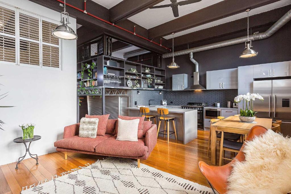 a living room with a red couch and a kitchen at Boutique Stays - Loft on Rose in Melbourne