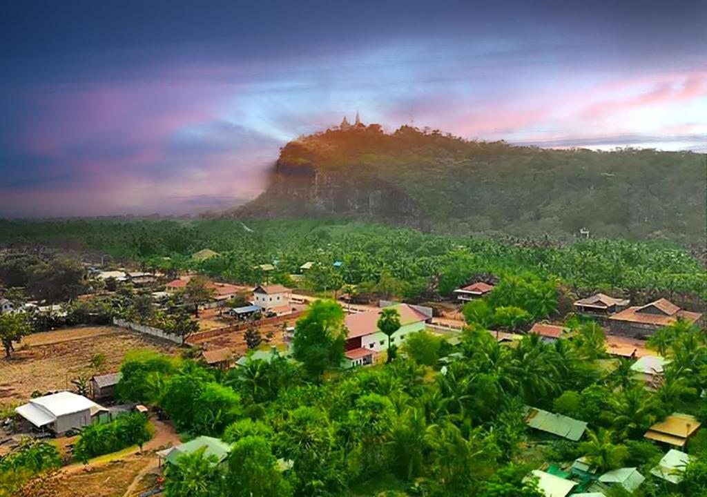 a small village with a mountain in the background at Family Batcave Homestay in Battambang