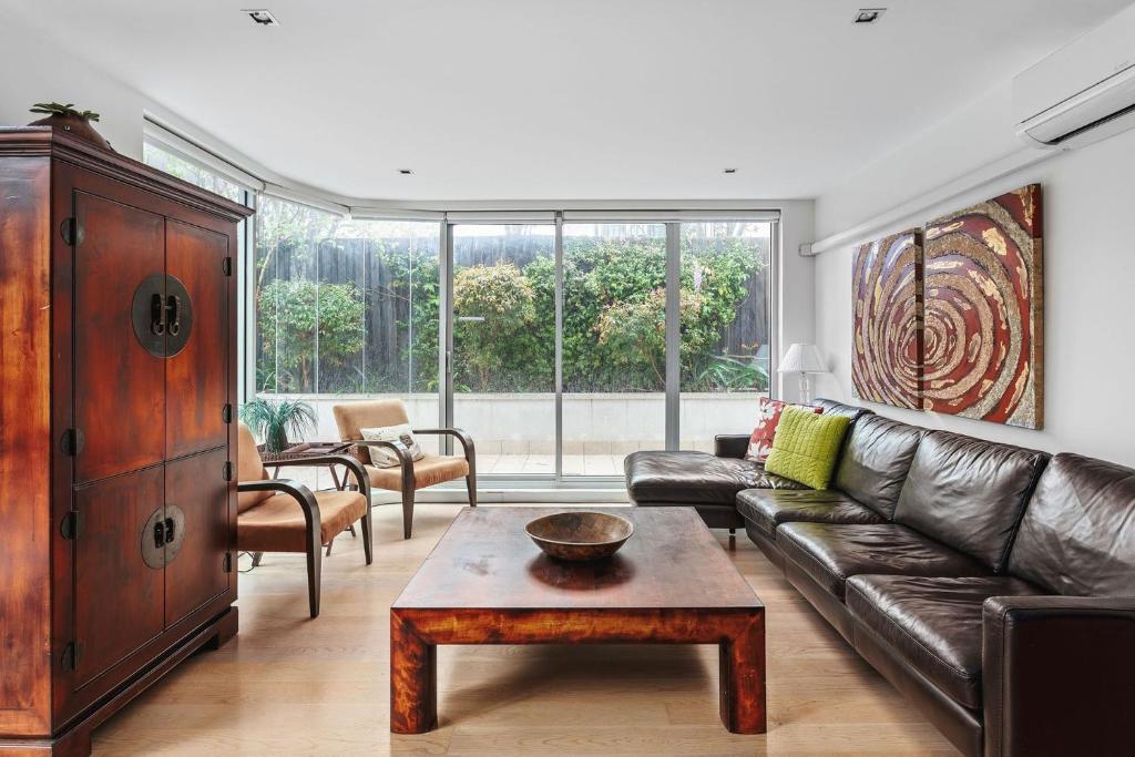 ein Wohnzimmer mit einem Ledersofa und einem Couchtisch in der Unterkunft Boutique Stays - Lalique in Melbourne