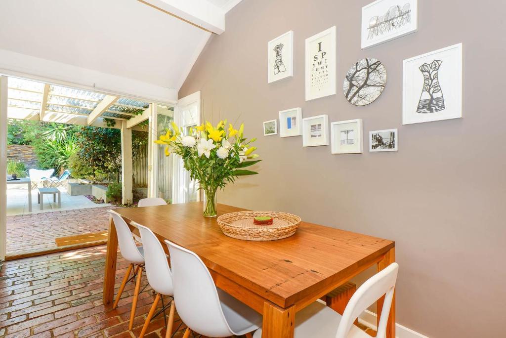 una mesa de comedor con sillas blancas y un jarrón de flores en Boutique Stays - Clifton Park, en Melbourne