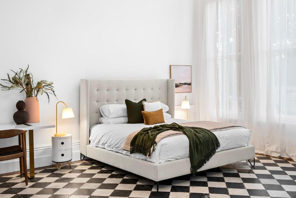 a bedroom with a white bed with a checkered floor at Boutique Stays - The Vault in Melbourne