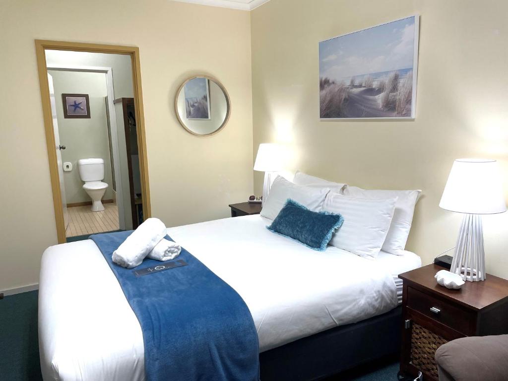 Cette chambre comprend un grand lit et un miroir. dans l'établissement City Heart Motel Warrnambool, à Warrnambool