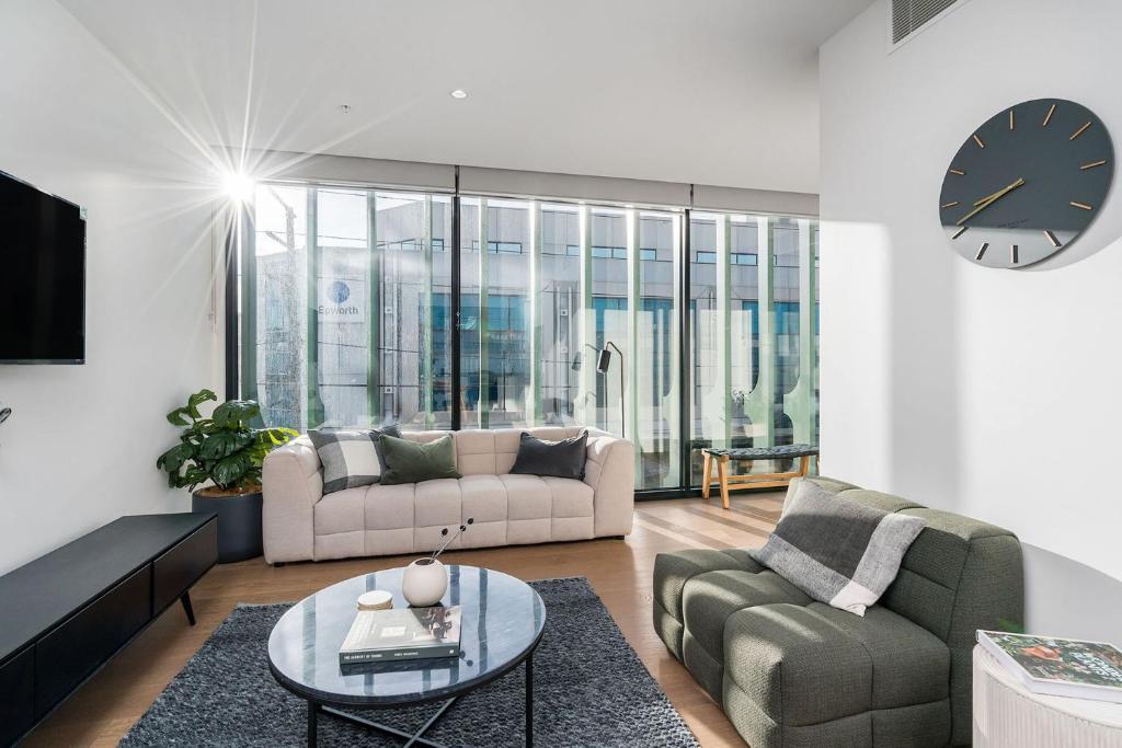 - un salon avec un canapé, une table et un réveil dans l'établissement Boutique Stays - Axel Apartments 201 The Clarke, à Melbourne