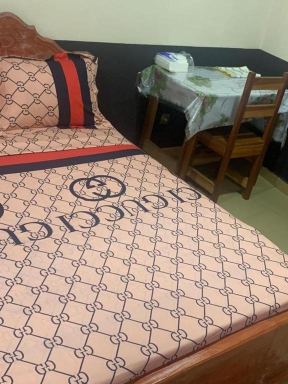 a bedroom with a bed and a table and a chair at Sunrise Center Ngousso Yaounde in Yaoundé