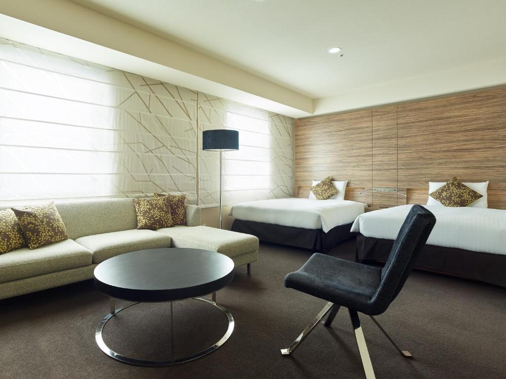 札幌市にある三井ガーデンホテル札幌のベッド2台、ソファ、テーブルが備わるホテルルームです。