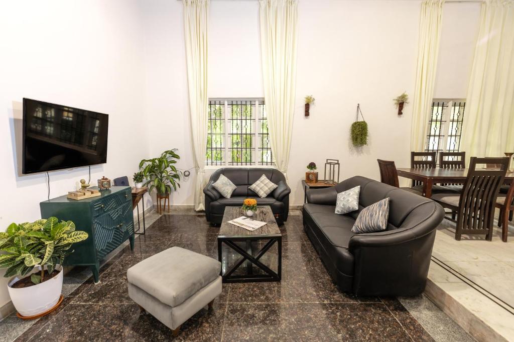 een woonkamer met banken en een flatscreen-tv bij Cozy 4BHK Villa in Bangalore