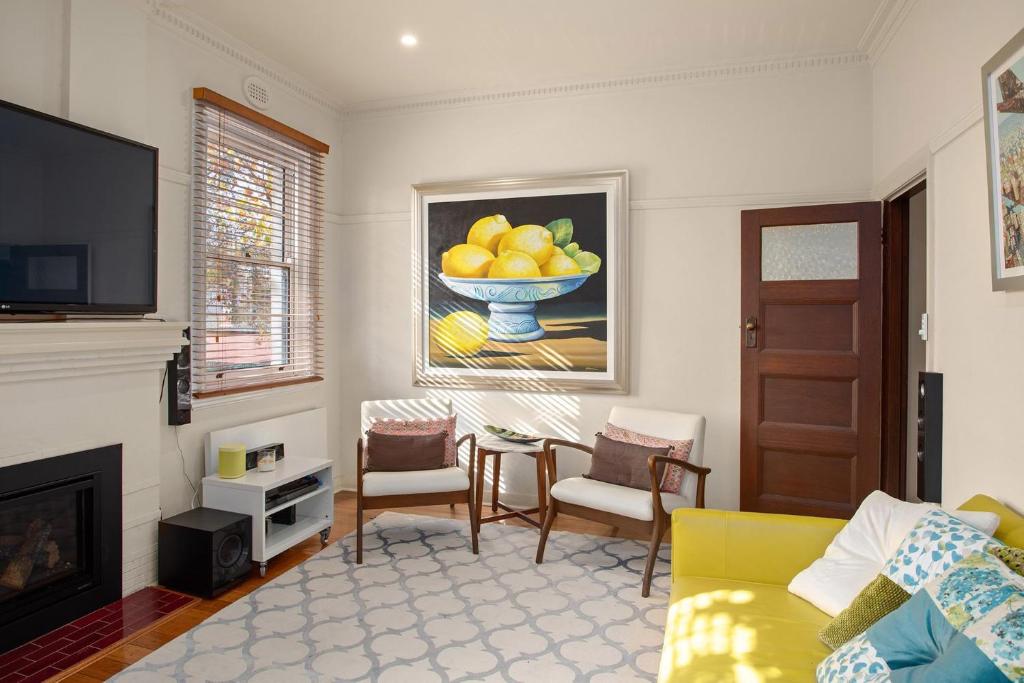 a living room with a yellow couch and a bowl of fruit at Boutique Stays - Cherrybombe in Melbourne