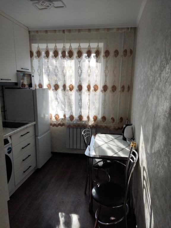 een kleine keuken met een tafel en een raam bij Квартира in Karagandy