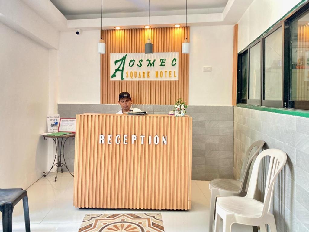 a man standing behind a reception desk in a lobby at Aosmec Square Hotel in Mactan