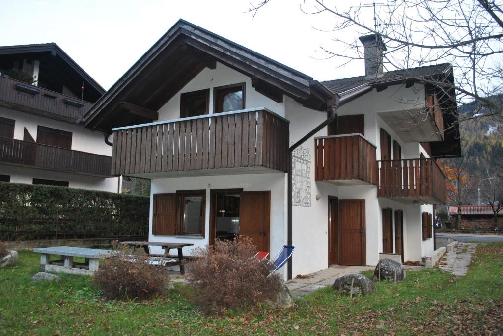 Casa blanca con balcones de madera y mesa de picnic en La Pineta - Appartamenti In Villetta, en Pinzolo