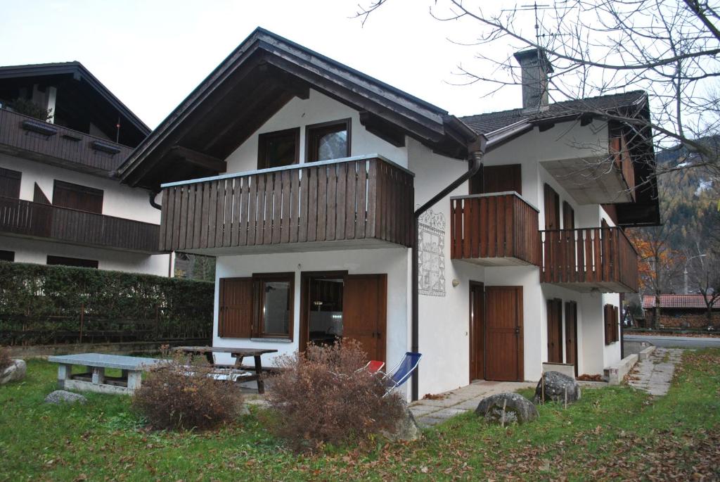 a white house with wooden balconies and a picnic table at La Pineta - Appartamenti In Villetta in Pinzolo