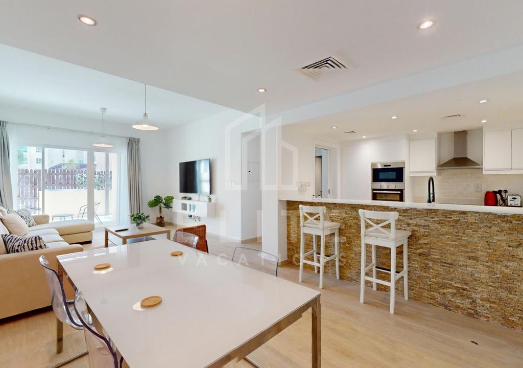 eine Küche und ein Wohnzimmer mit einem weißen Tisch und Stühlen in der Unterkunft Fully Furnished 1BR Apartment with Stunning Interior in Dubai