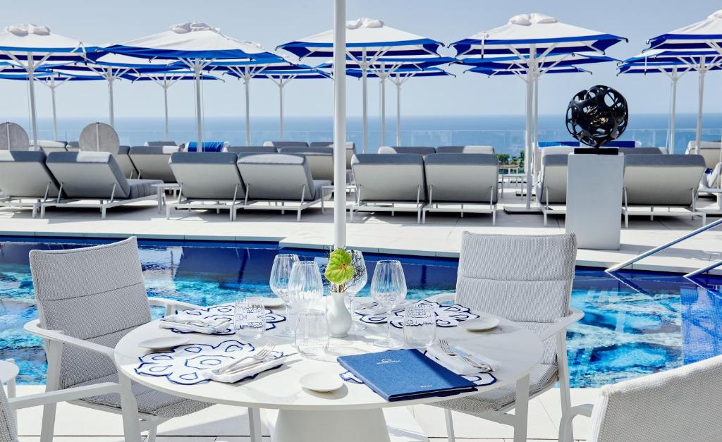 een witte tafel en stoelen naast een zwembad bij Hotel Scalinatella in Capri