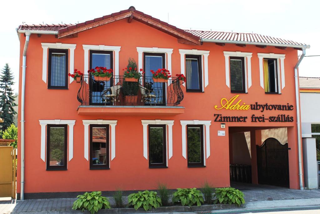 una casa roja con flores en el balcón en Adria penzión, en Štúrovo