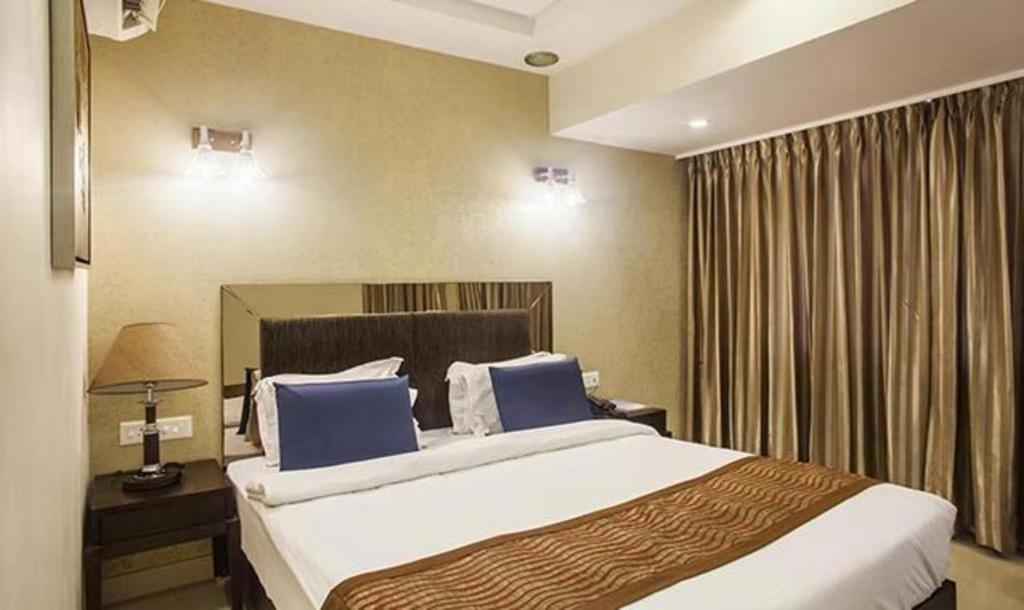 a hotel room with a large bed with blue pillows at FabHotel Prime Hema's Supreme in Visakhapatnam