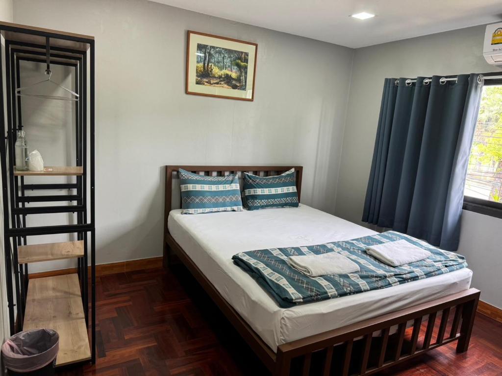 1 dormitorio con 1 cama con cortinas azules en Chill @ Phetchaburi, en Phetchaburi