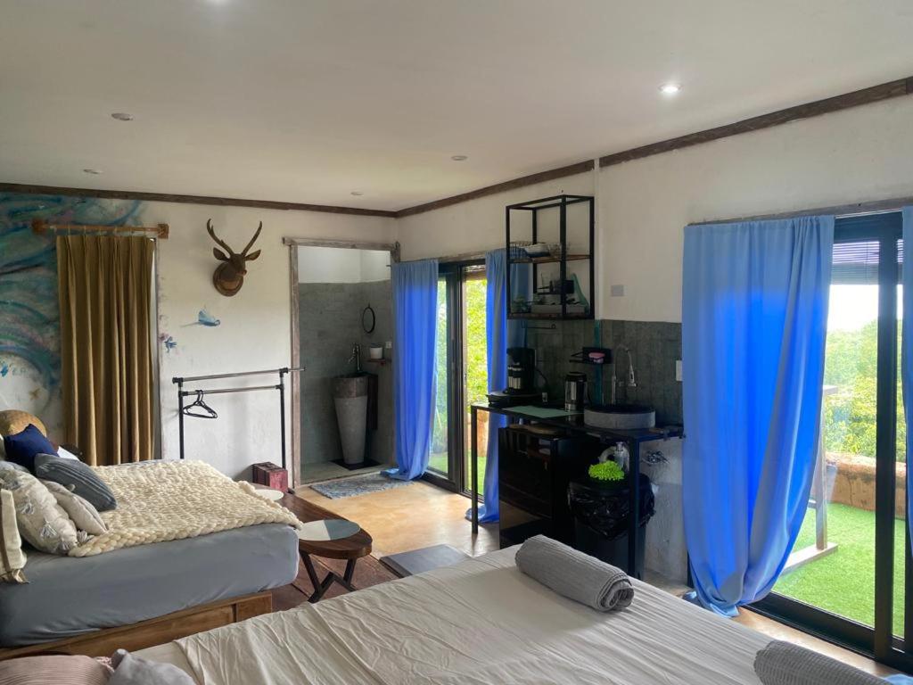 a bedroom with two beds and blue curtains at Sea view hills bungalow in Torio