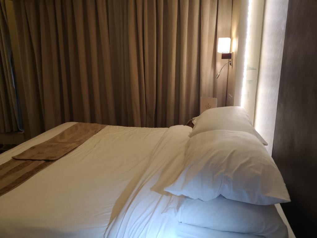 a bed with white sheets and pillows in a room at فندق تحسين العزيزية-Tahseen Azizia Hotel in Makkah