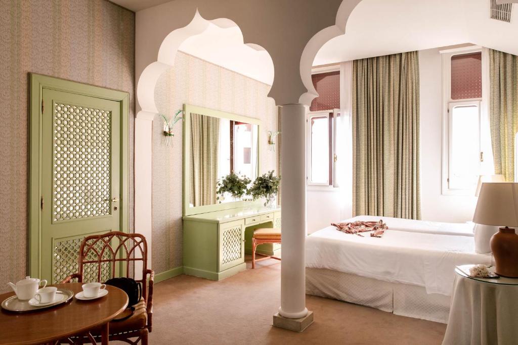 リード・ディ・ヴェネツィアにあるホテル エクセルシオール ヴェニスのベッドルーム(ベッド1台、テーブル、鏡付)