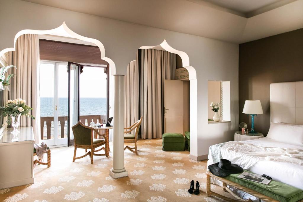 a hotel room with a bed and a table and a room at Hotel Excelsior Venice in Venice-Lido