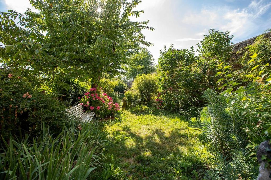 un jardin avec un banc, des fleurs et des arbres dans l'établissement Suite & Castle - Au Pied du Château d'Annecy, à Annecy