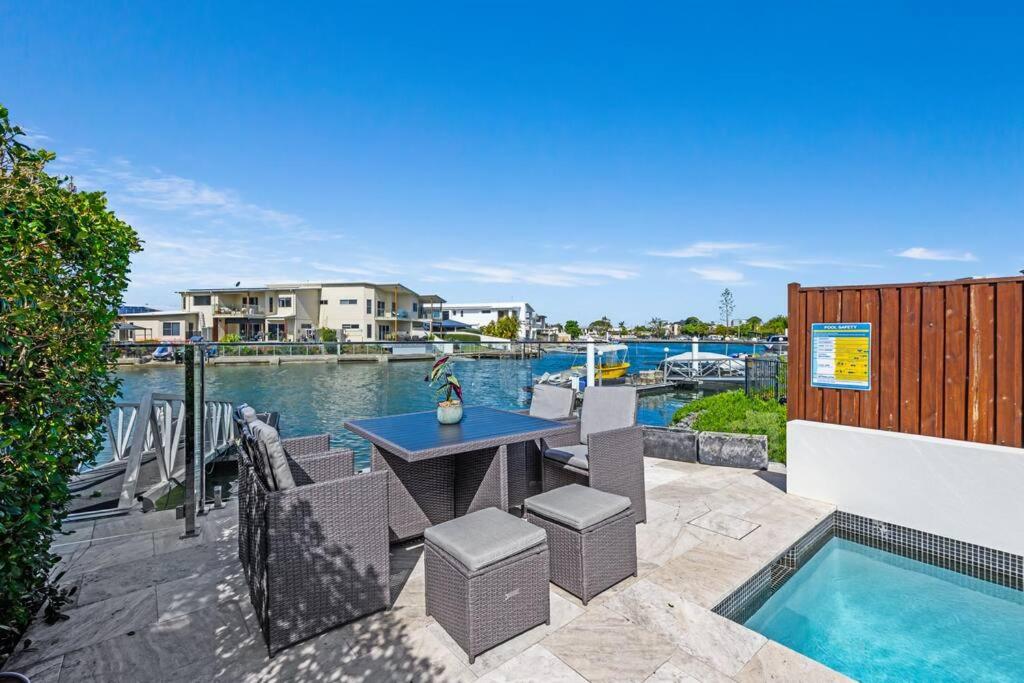 um pátio com uma mesa e cadeiras ao lado de uma piscina em Luxury Modern Waterfront House em Gold Coast