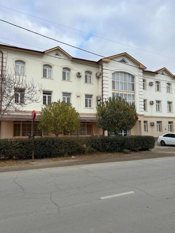 ein großes weißes Gebäude an der Straßenseite in der Unterkunft Hotel Jipek Joli in Nukus